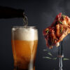 Beer and grilled pork ribs. Grilled meat sprinkled with rosemary on a black background.