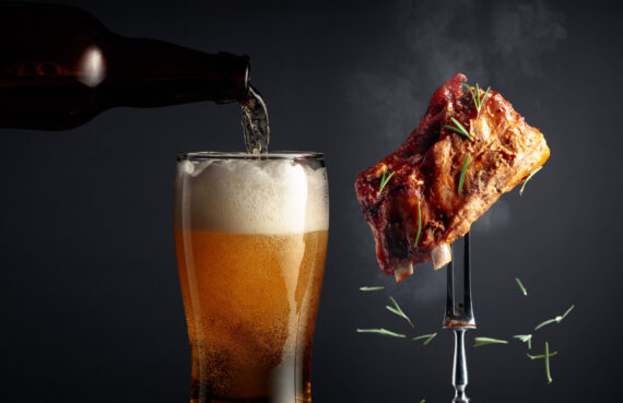 Beer and grilled pork ribs. Grilled meat sprinkled with rosemary on a black background.